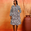 Elegant monochrome Ankara wrap dress featuring a shawl collar, long sleeves, and functional side pockets for effortless style and comfort.