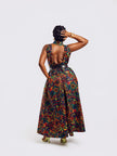 Full-length back view of a woman wearing the Amazin Apparels Kaleidoscope Gown, showing a large circular keyhole cutout and hidden elastic waistband in a vibrant floral African print.