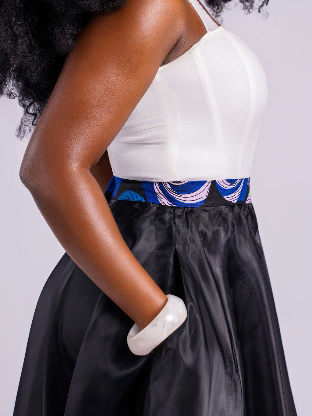 Close up side view of a model wearing the sheer, unlined black organdy maxi skirt with her hand in the pockets. 