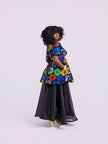 side view of a model wearing The Swirl Peplum & Organdy Set with a hand in the side pocket of the Swirl Peplum.