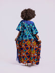 back view of a woman in the Amazin Apparels Aso Oke Fusion Gown, featuring a blue pinstripe top, bold floral skirt, and floor-length shredded Aso Oke fringe on the sides.