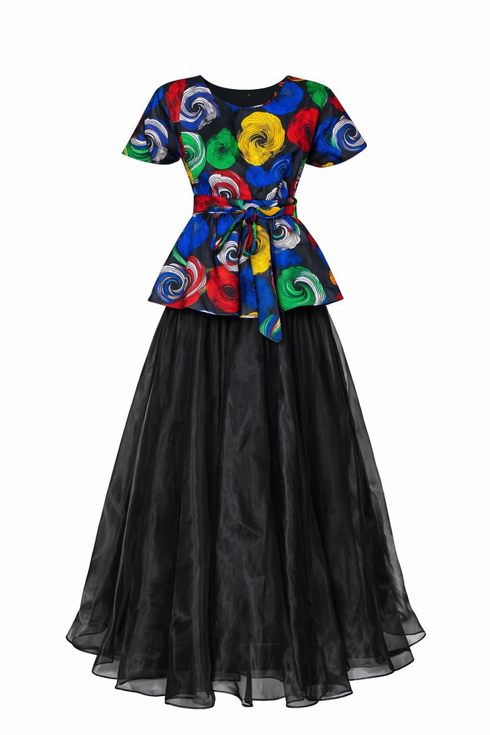 A two-piece set featuring a multi-colored swirl print peplum top and a sheer, unlined black organdy maxi skirt with two hidden pockets on both piece, on a white background.
