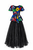 A two-piece set featuring a multi-colored swirl print peplum top and a sheer, unlined black organdy maxi skirt with two hidden pockets on both piece, on a white background.