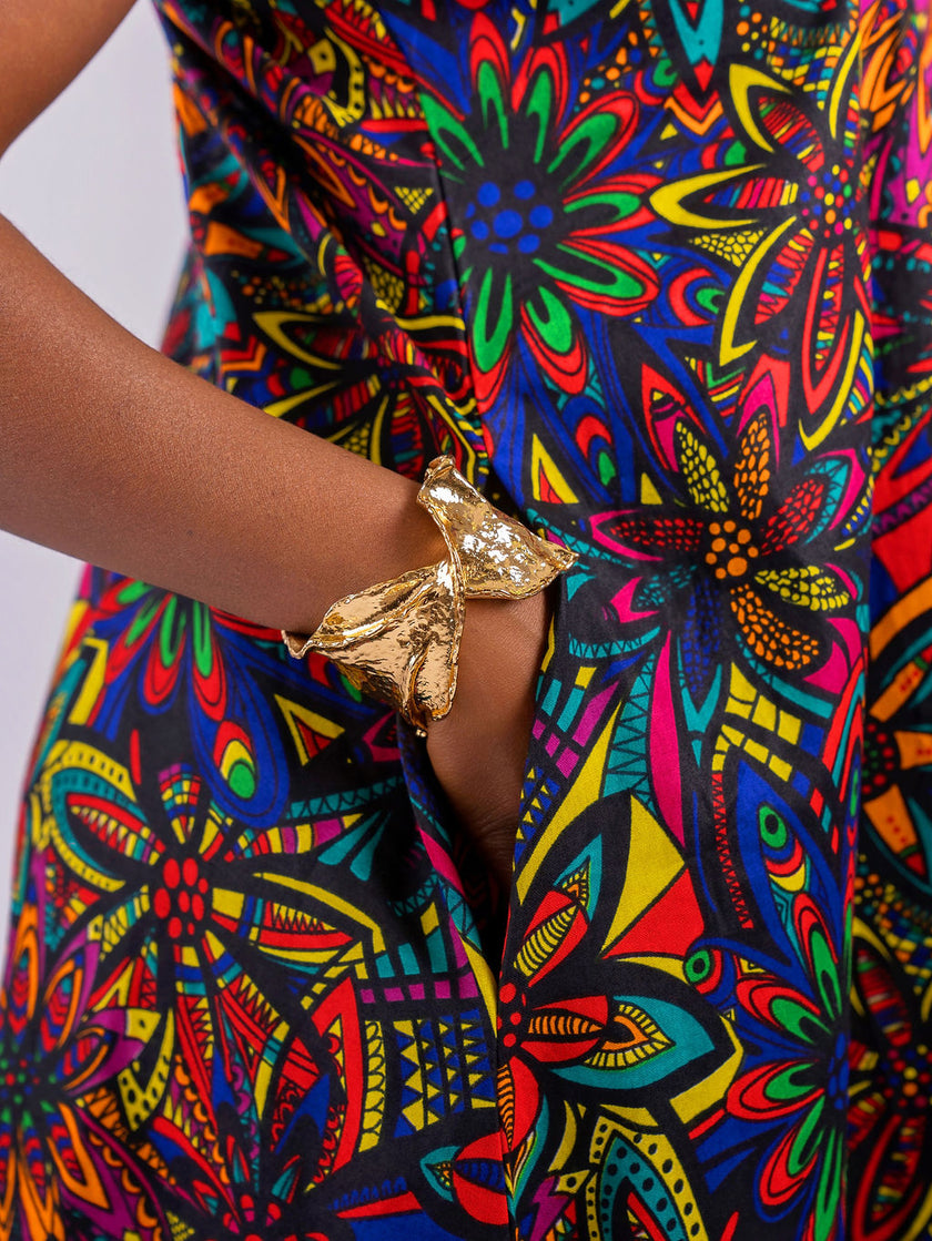A hand tucked into the hidden side-seam pocket of the Kaleidoscope floral maxi dress, highlighting functional design