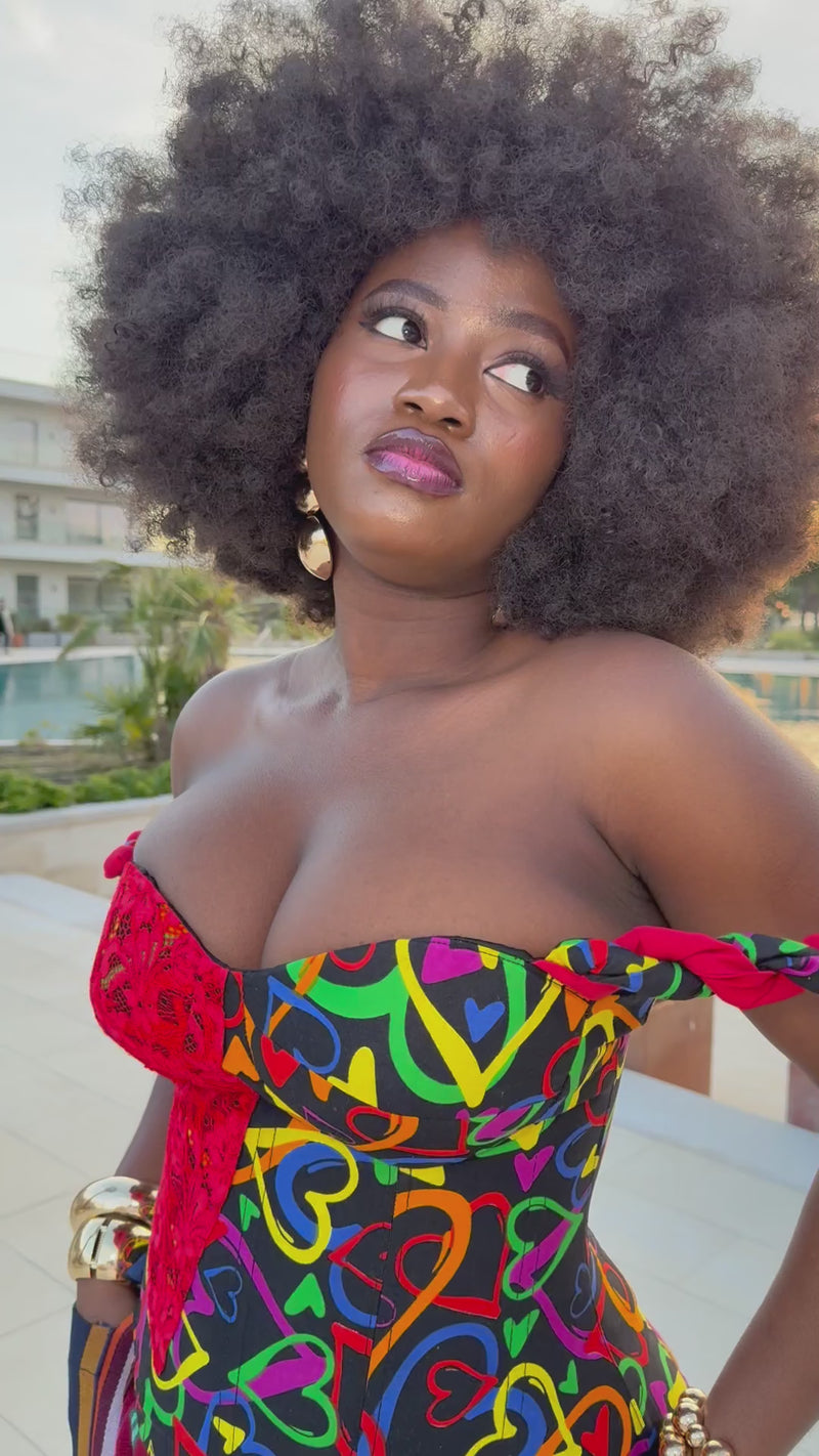 Video of model giving a 360-degree view of the Ànìké Ankara corset blouse, featuring sweetheart neckline, braided straps, structured silhouette, and lace-up back. Handmade with vibrant multicoloured African print heart-patterned cotton, this bustier top combines traditional Ankara style with modern elegance, perfect for weddings, cultural events, and evening parties.